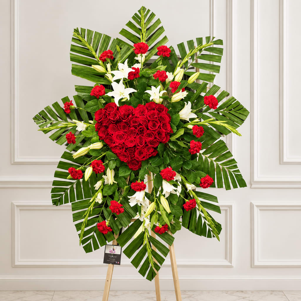 Heart-shaped red rose standing spray with white lilies and palm leaves