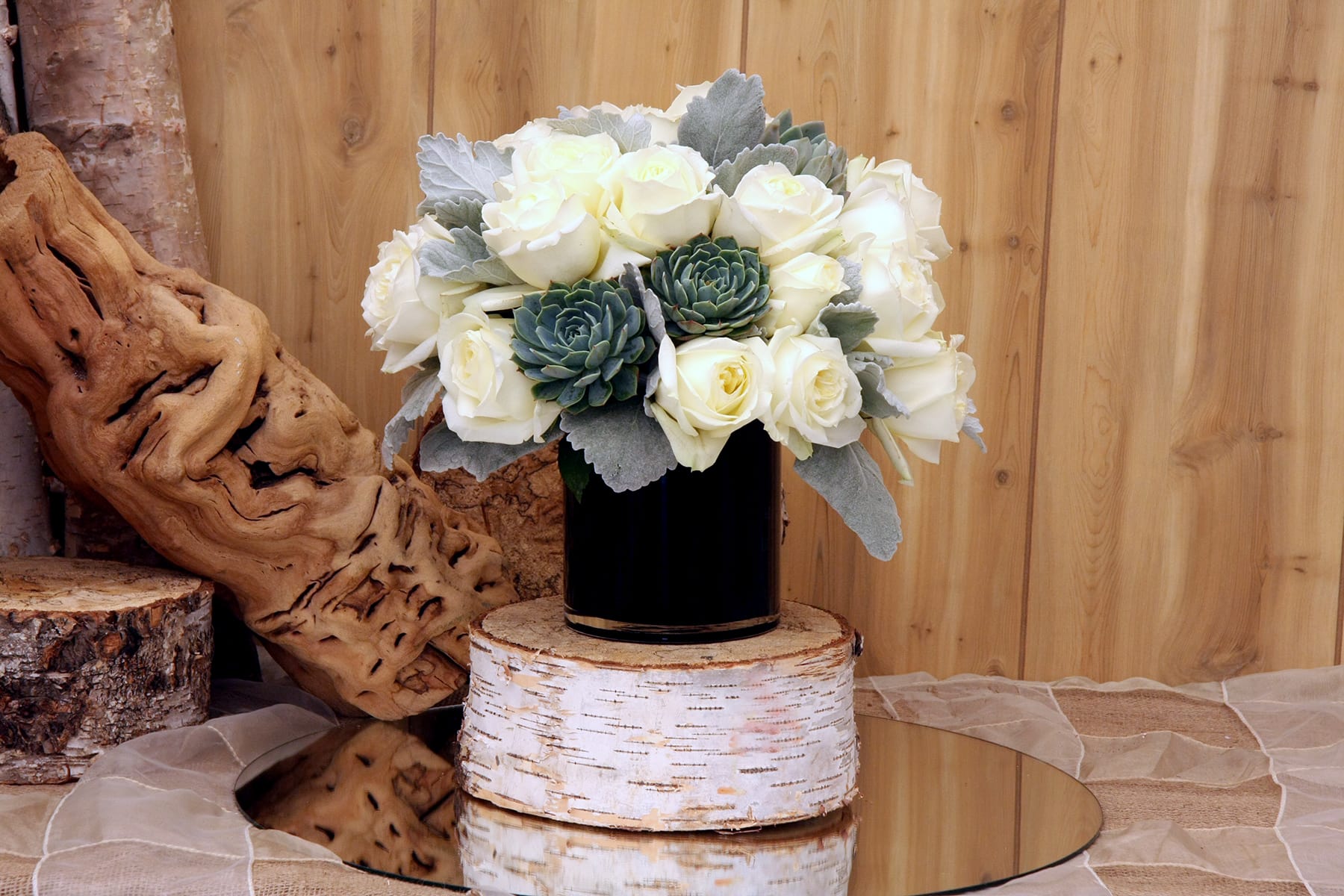 White roses and green succulents in a black vase
