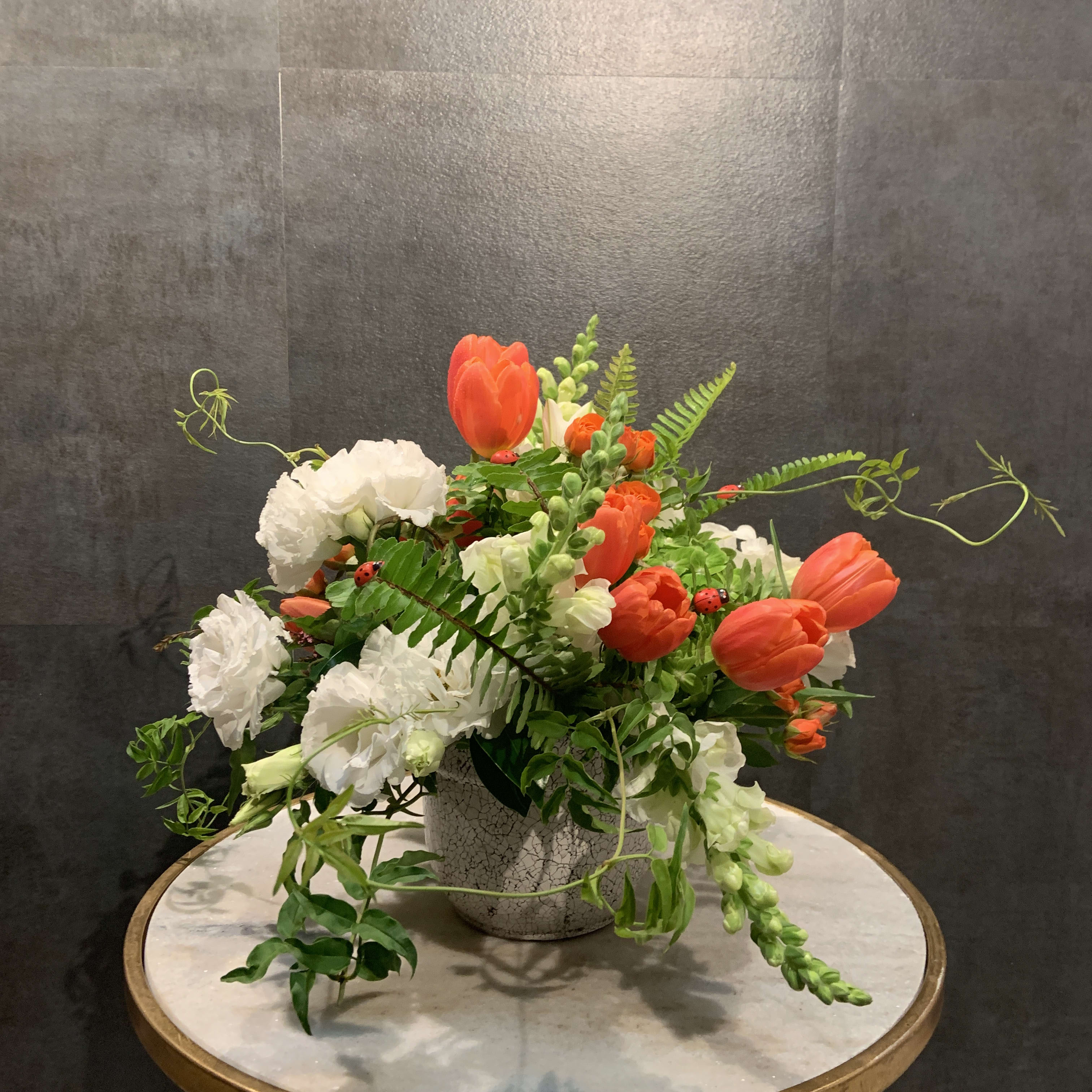 Orange tulips and white carnations in a textured vase