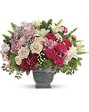 Mixed bouquet of pink roses, lilies, and orchids in a gray vase