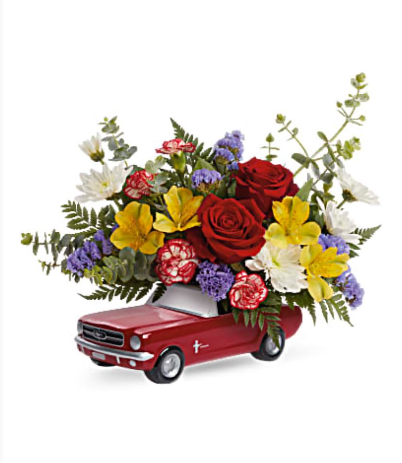 Flower arrangement in a red toy car with roses and mixed blooms