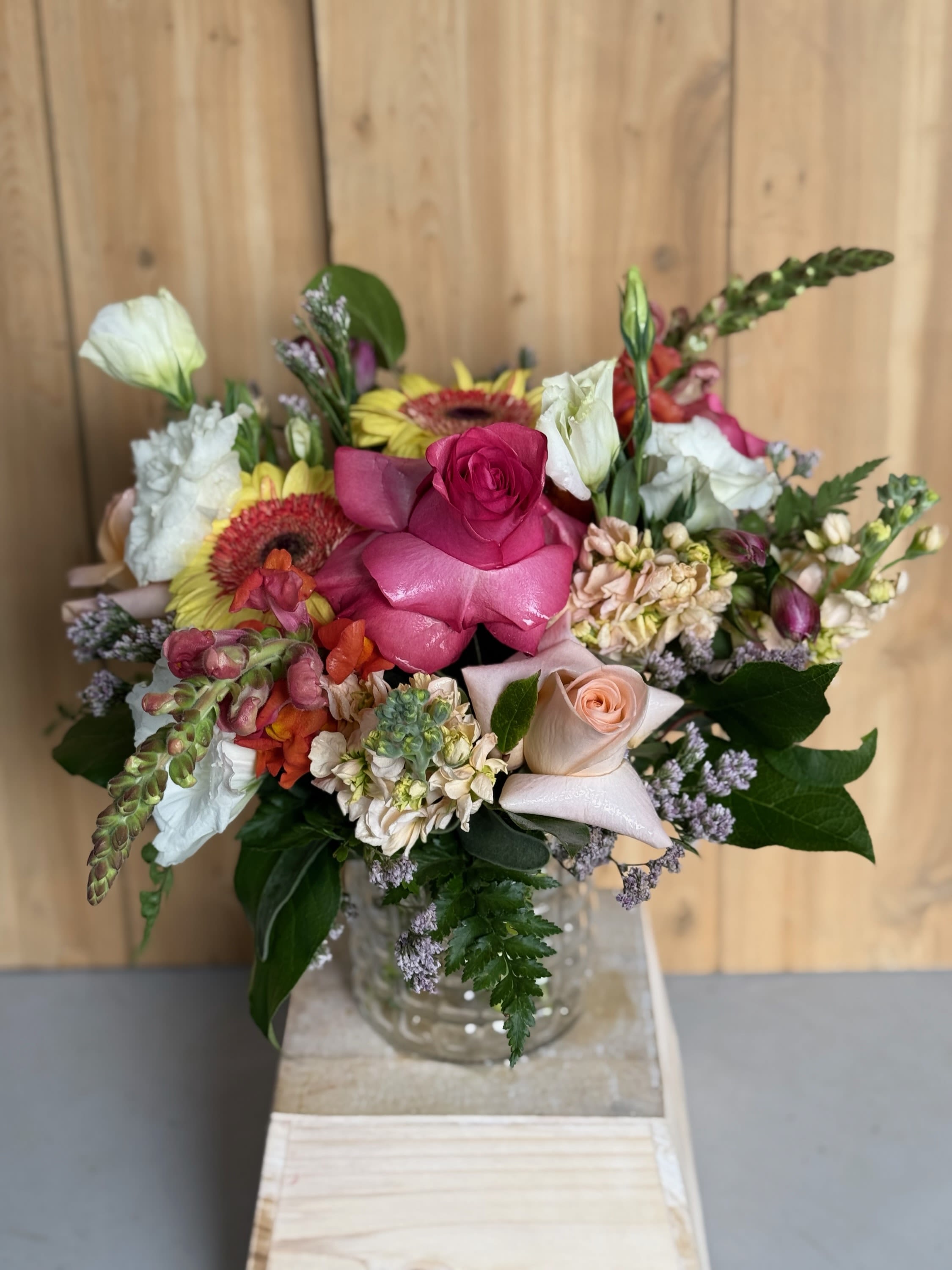 Mixed bouquet with pink roses, white blooms, and gerbera daisies in a glass vase