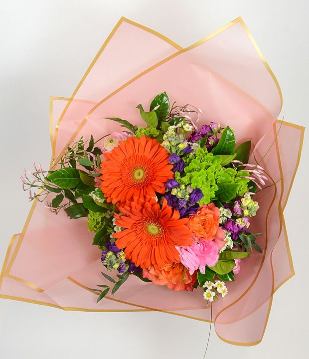 Bouquet of orange gerbera daisies and mixed flowers wrapped in pink paper