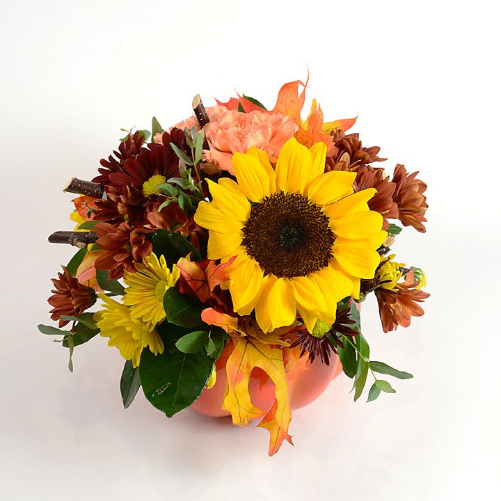Autumn bouquet with a sunflower and chrysanthemums in a peach vase