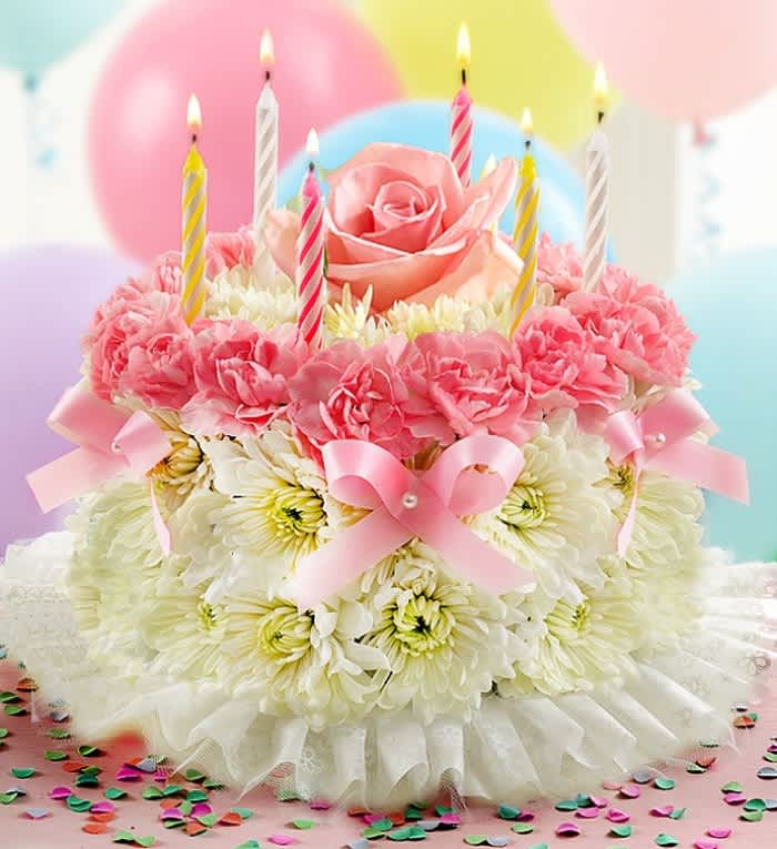 Pink and white floral cake with lit striped candles