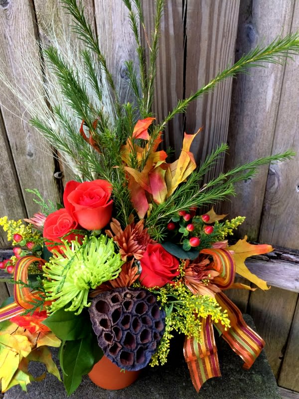 Autumn floral arrangement with red roses and mixed foliage in a vase