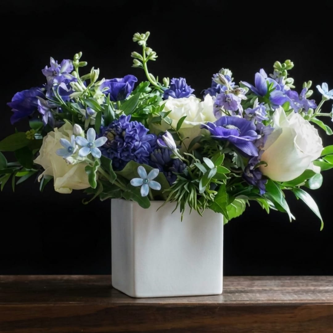 Blue and white floral arrangement in a white square vase