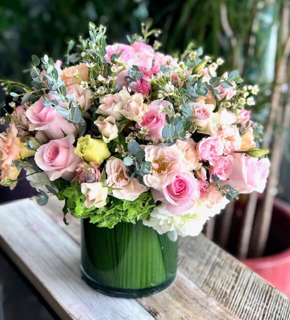 Pink and peach roses arranged in a green glass vase