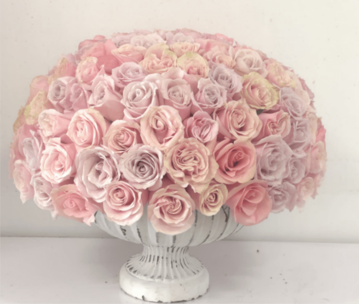 Round bouquet of pale pink roses in a white pedestal vase