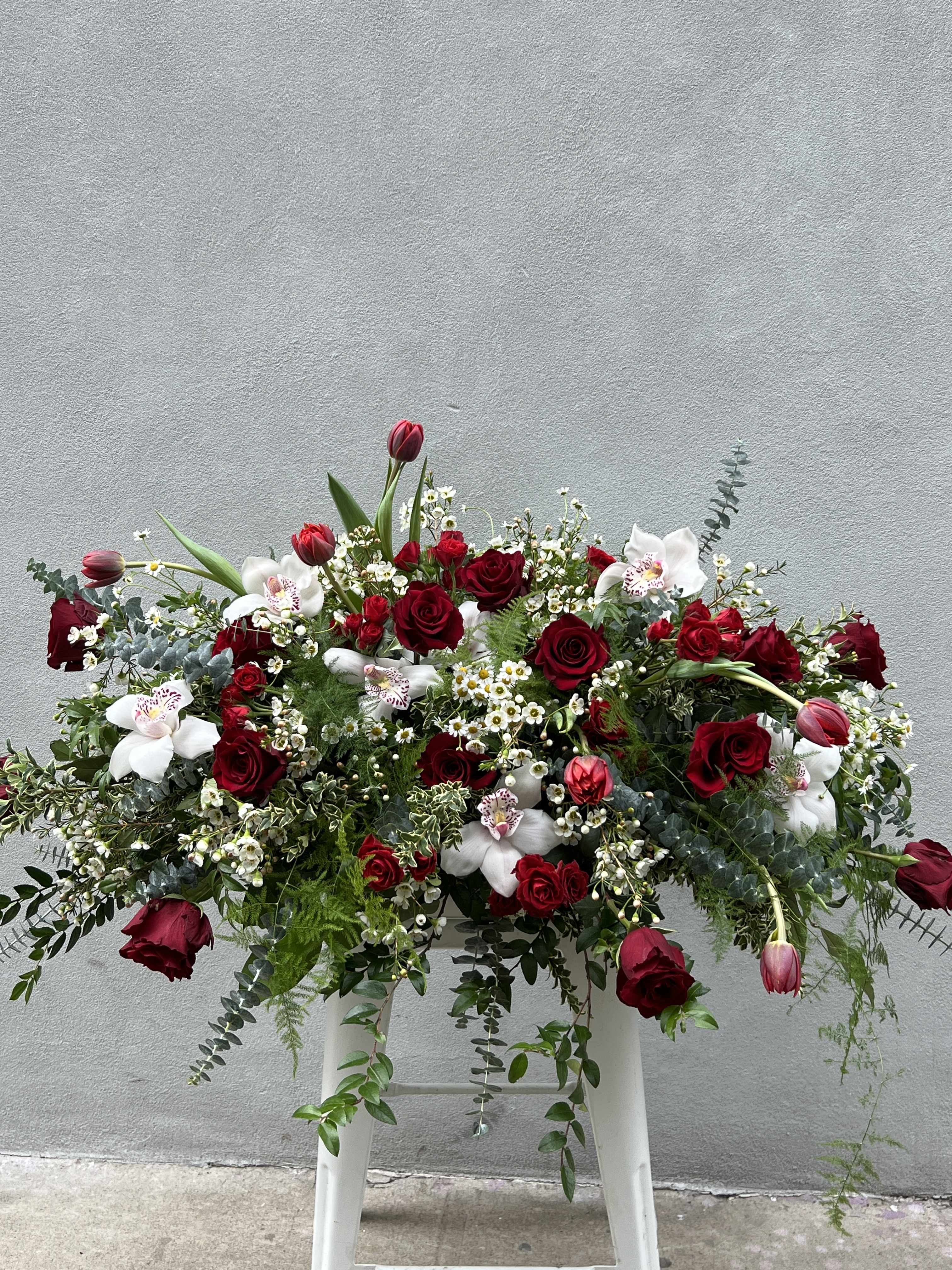 Large red and white floral arrangement with roses and orchids