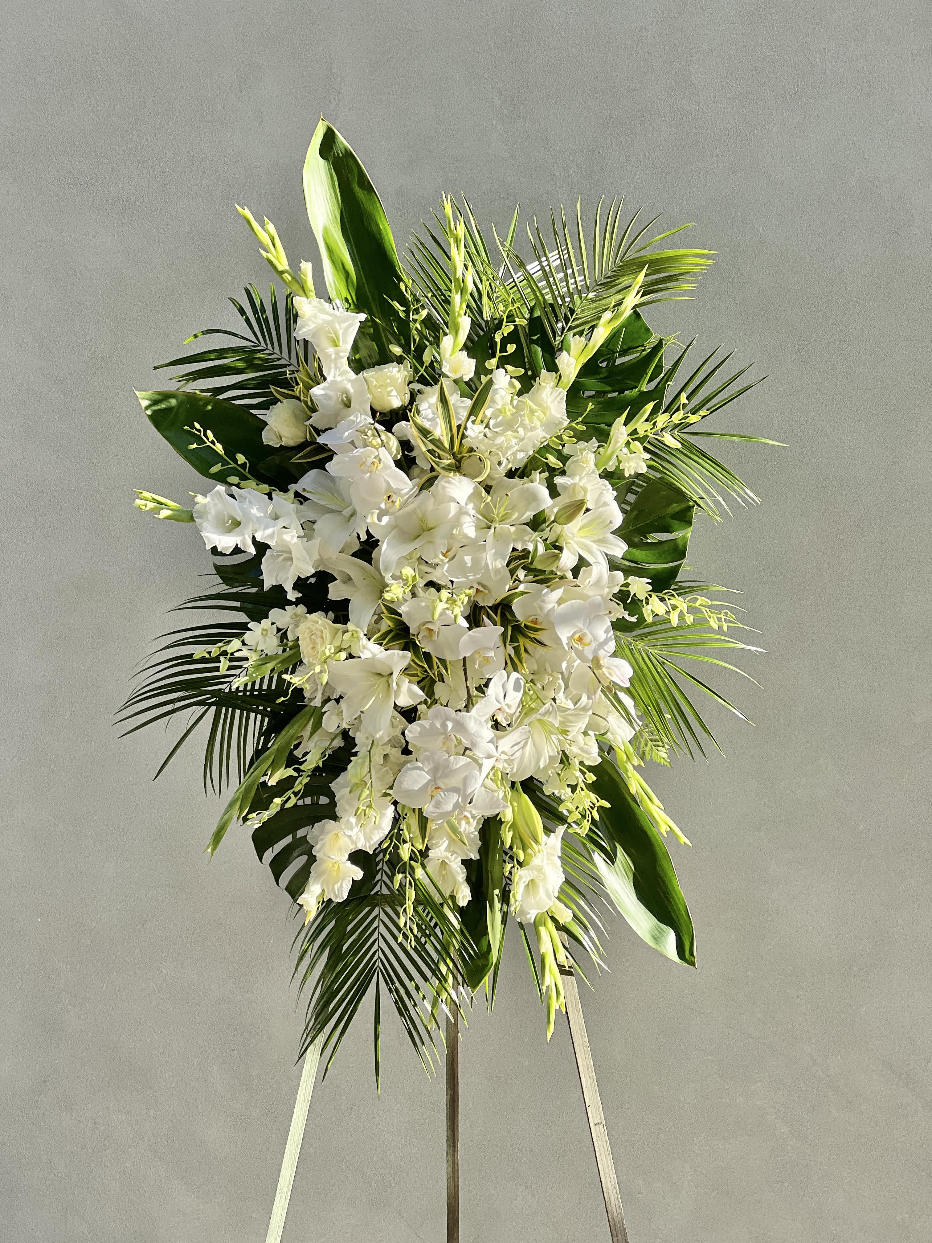 Aloha Funeral Spray - Inspired by the Hawaiin Islands, this spray if filled palm and ti leaves, gladiolus, oriental lilies, dendrobium orchids and phaelanopsis orchids.