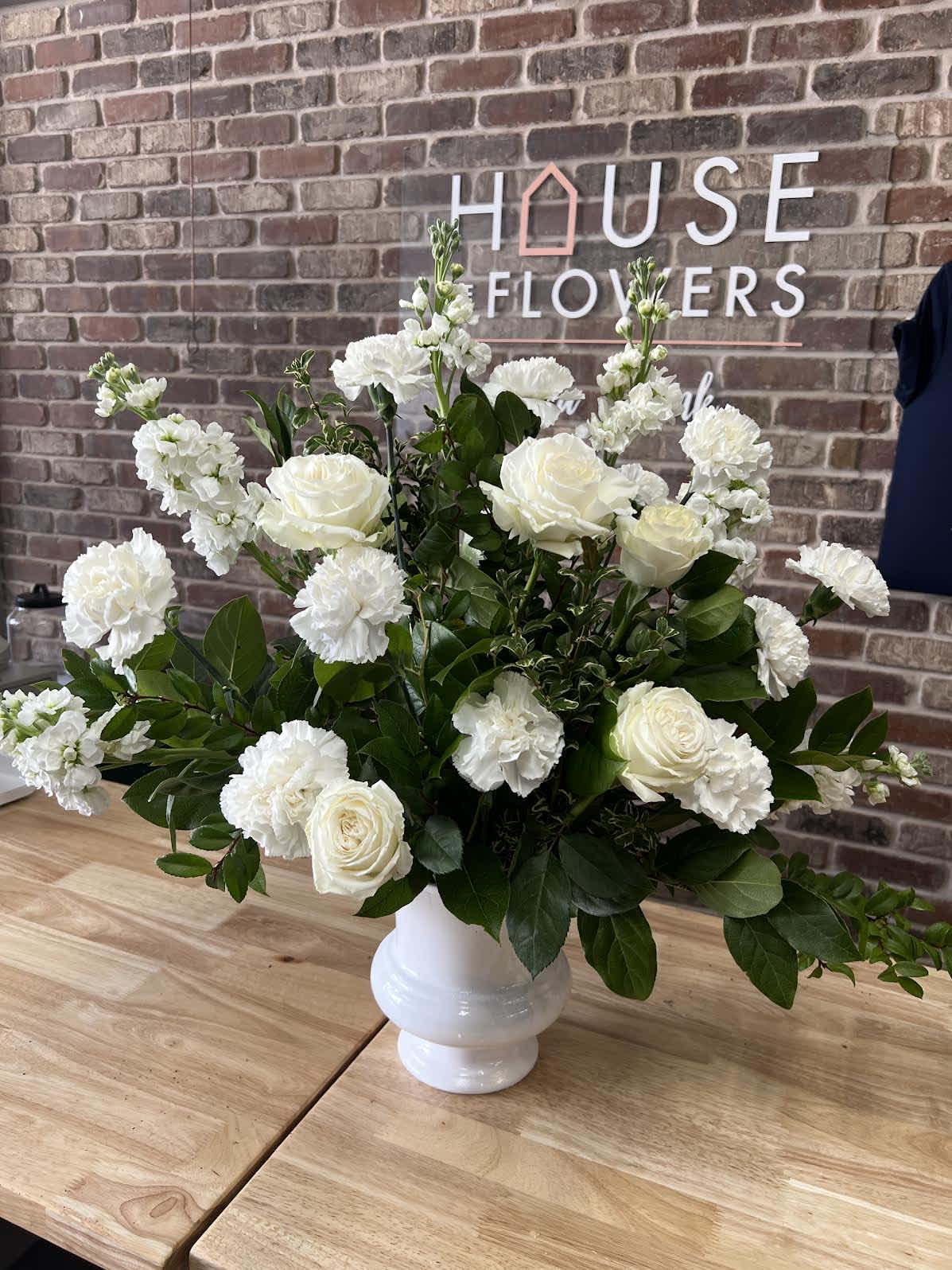 Kind &amp; Compassionate Urn Arrangement - White urn filled with dark green mixed foliages, fragrant stocks, carnations and roses.   Meaures 20in tall, 10in wide 