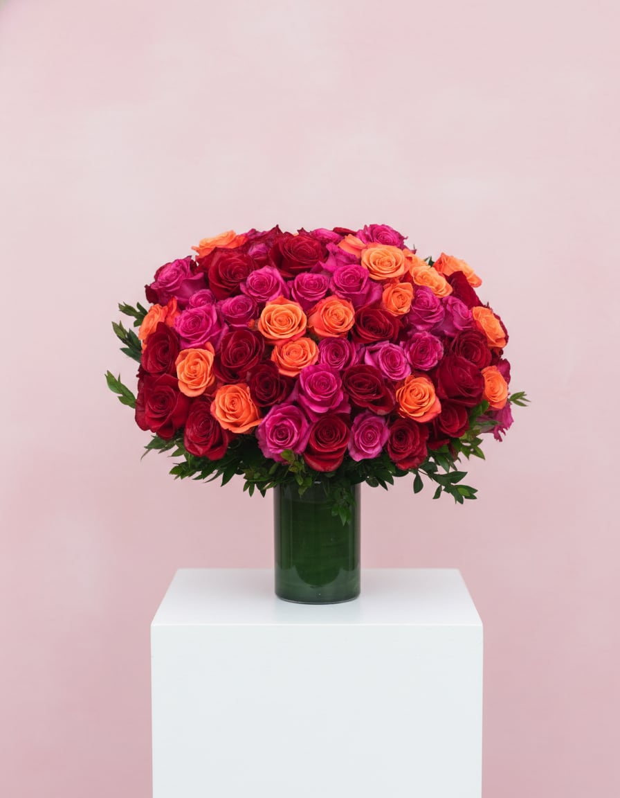 Bouquet of red, pink, and orange roses in a green glass vase