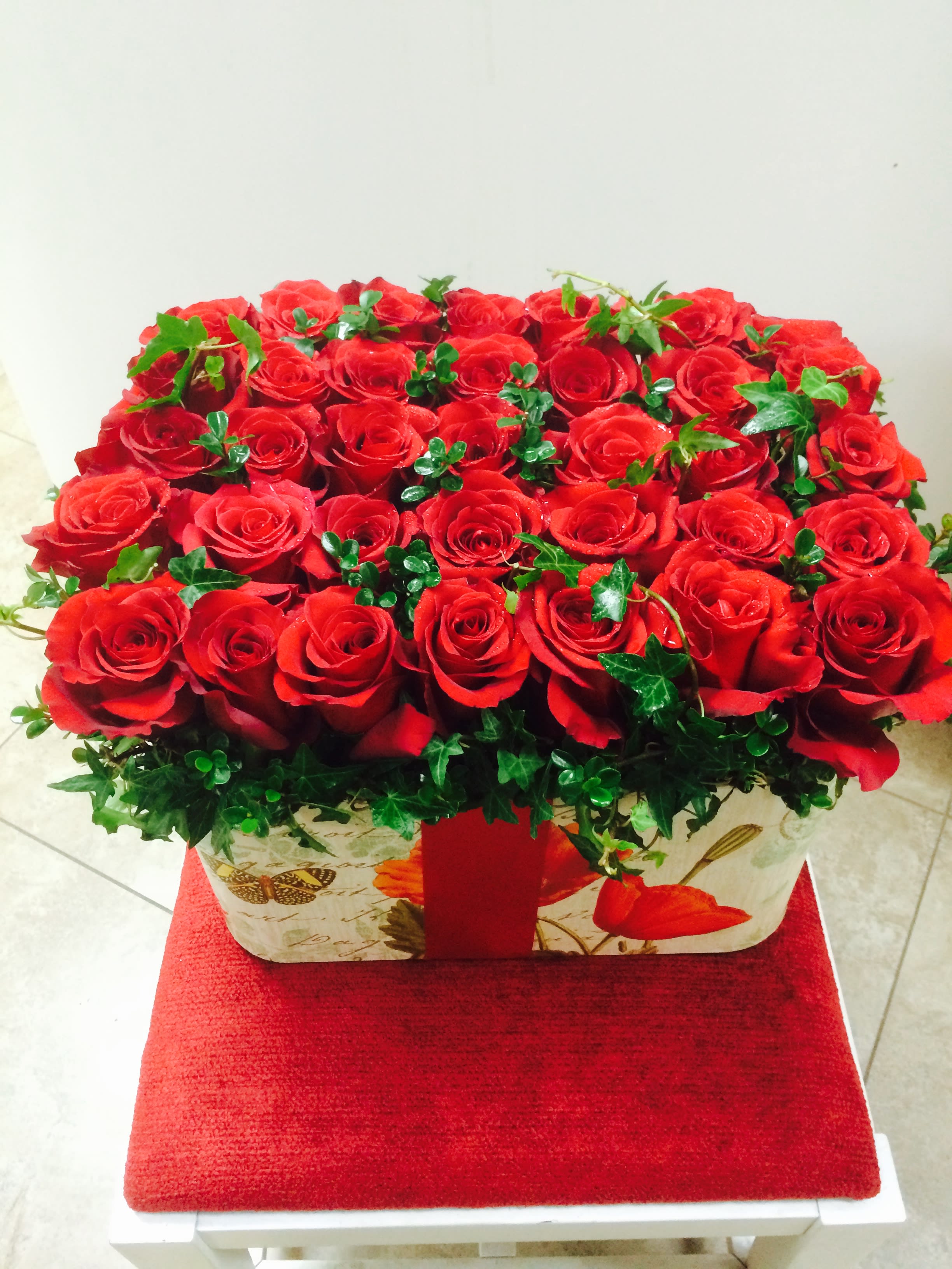 Red roses arranged in a rectangular gift box with ivy accents