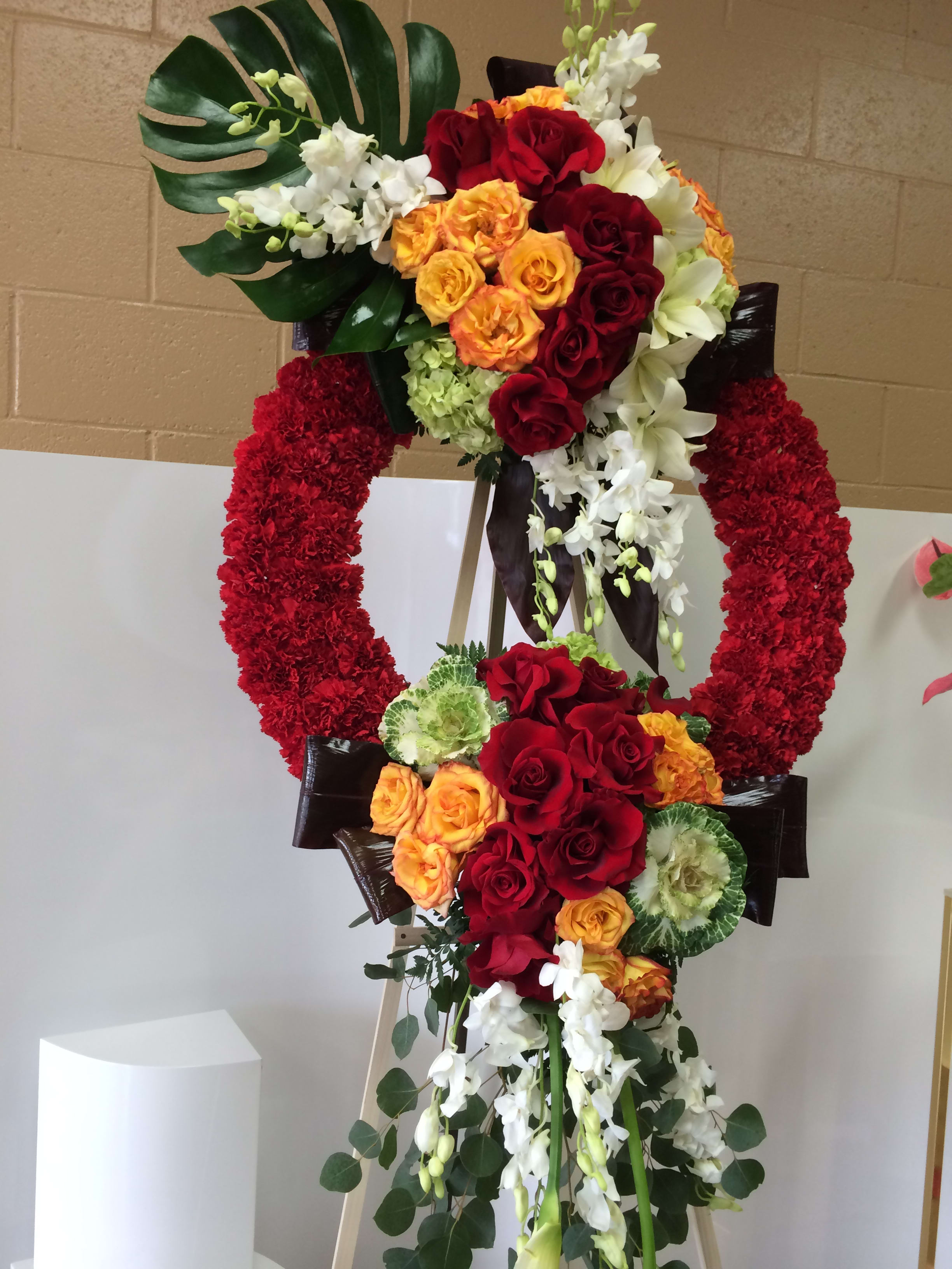Large floral standing wreath with red, orange, and white flowers