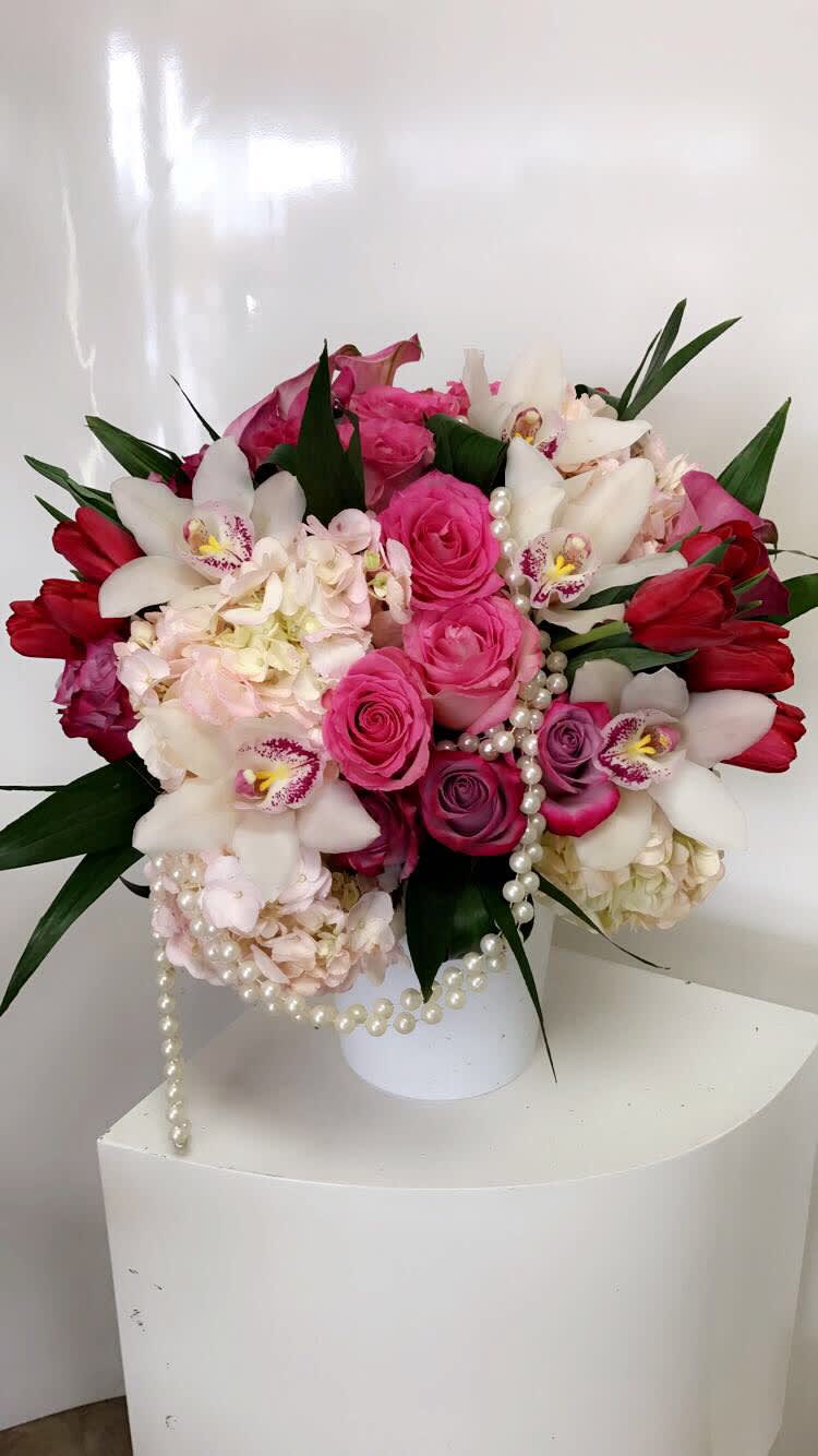 Pink and white floral arrangement in a white vase with pearl strands