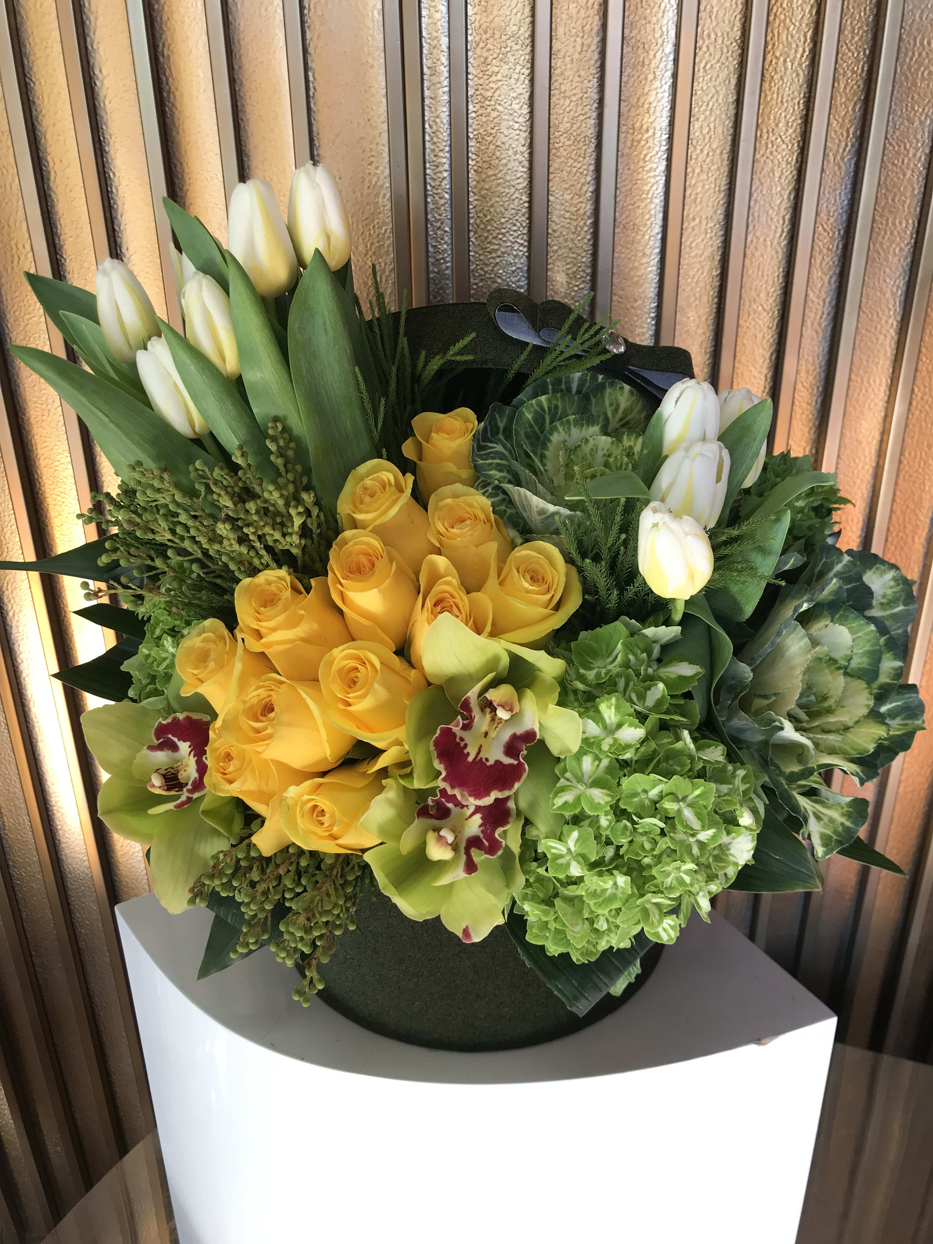 Yellow roses and white tulips in a round black container