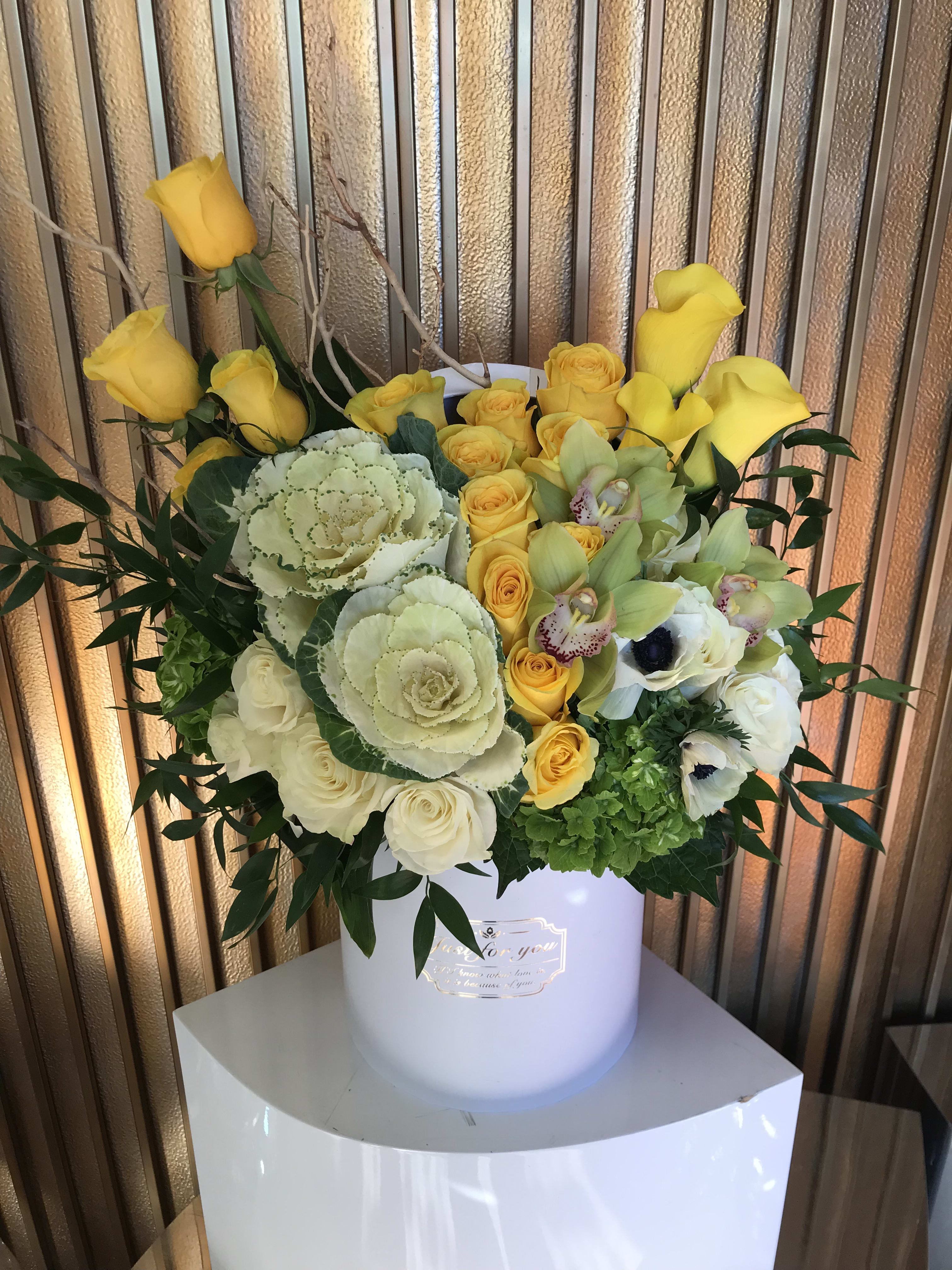 Yellow and white floral arrangement in a white hatbox