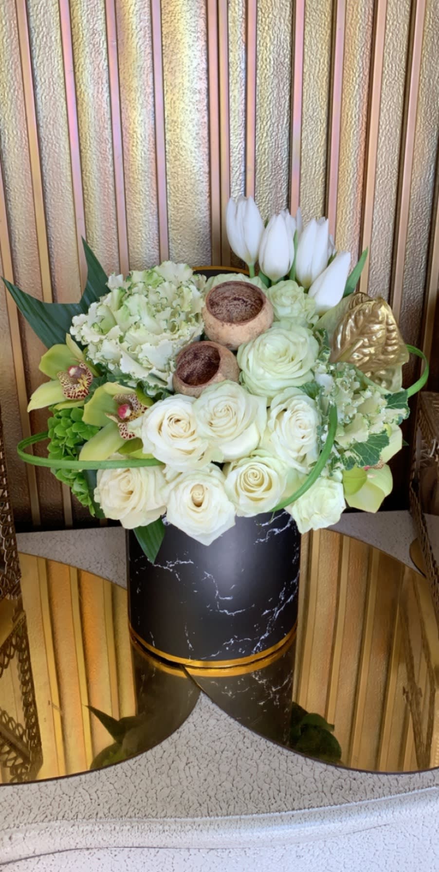 White roses and tulips arranged in a black vase with gold accents