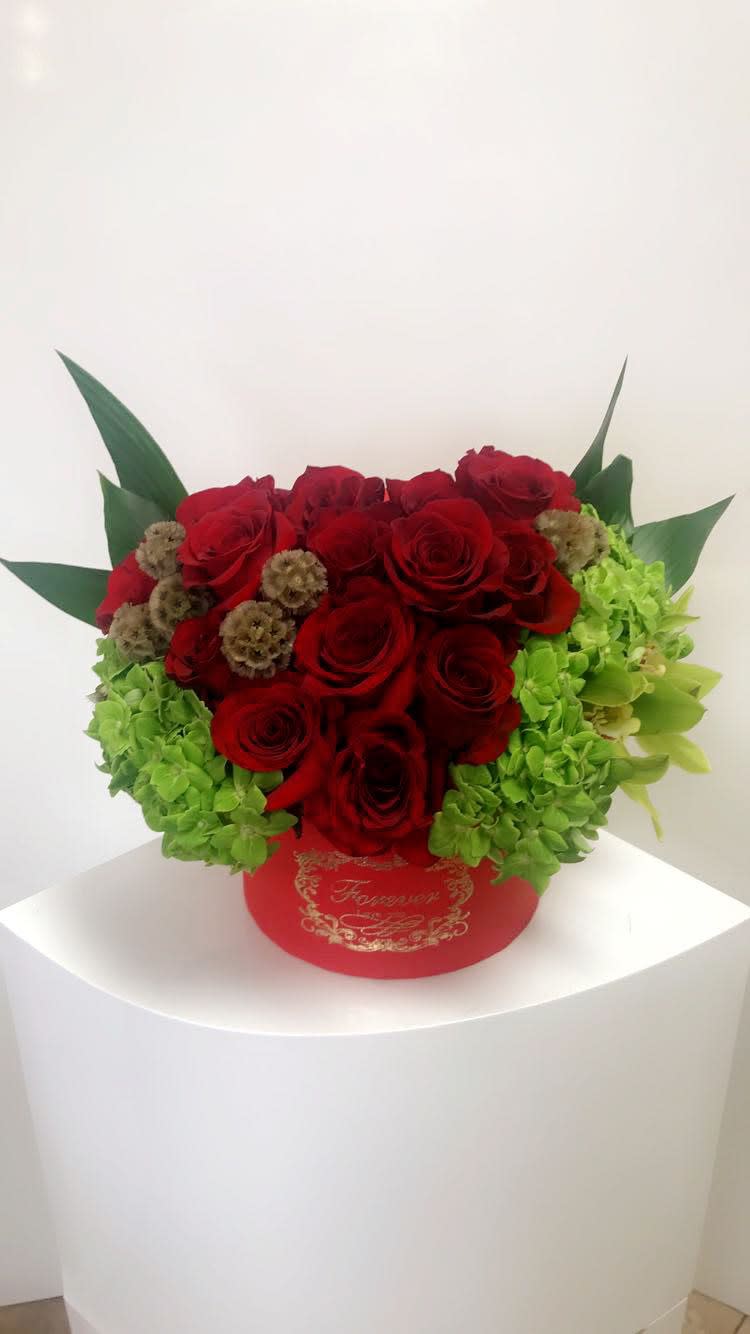 Red roses and green hydrangeas in a red round box
