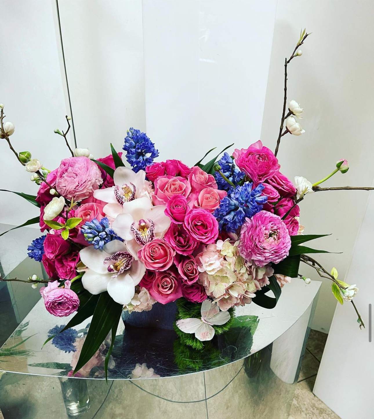 Pink and blue floral arrangement with orchids and roses in a vase