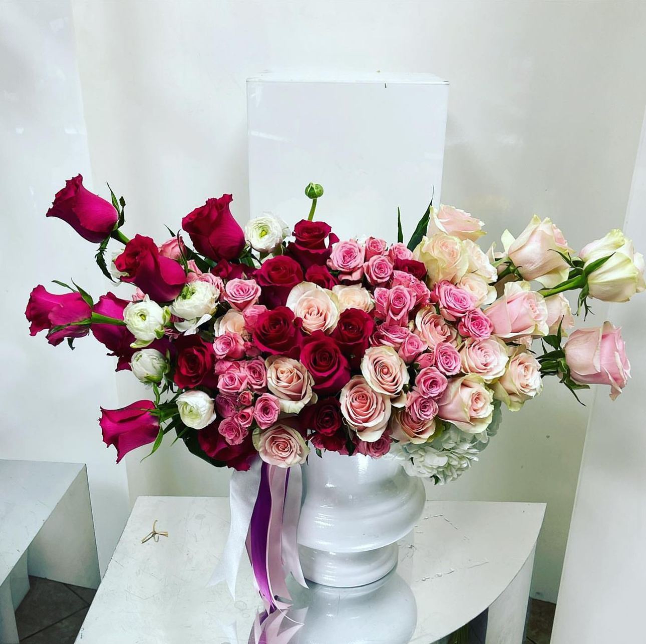 Bouquet of pink and red roses in a white pedestal vase