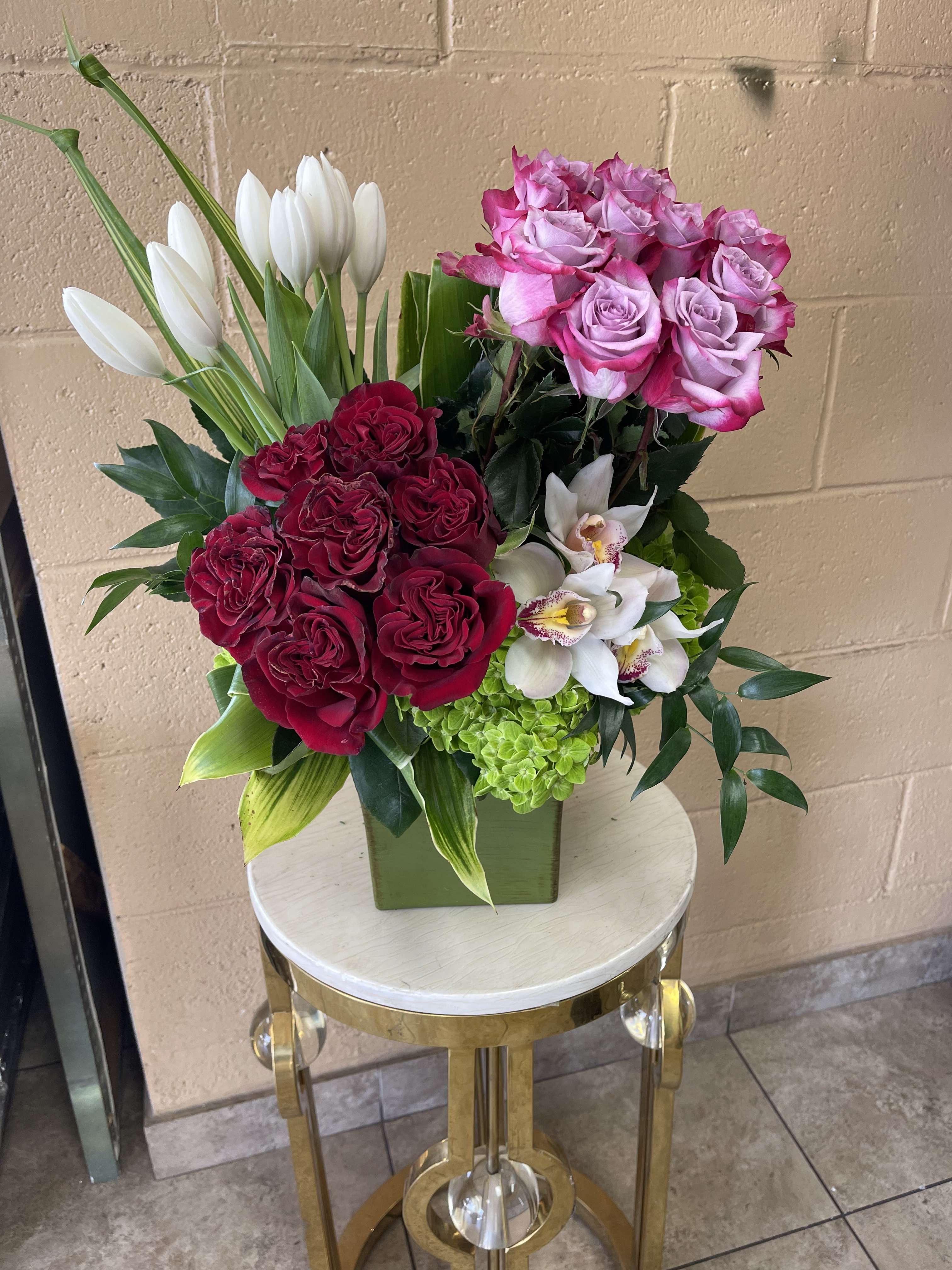 Mixed bouquet of pink and red roses with white tulips in a square vase