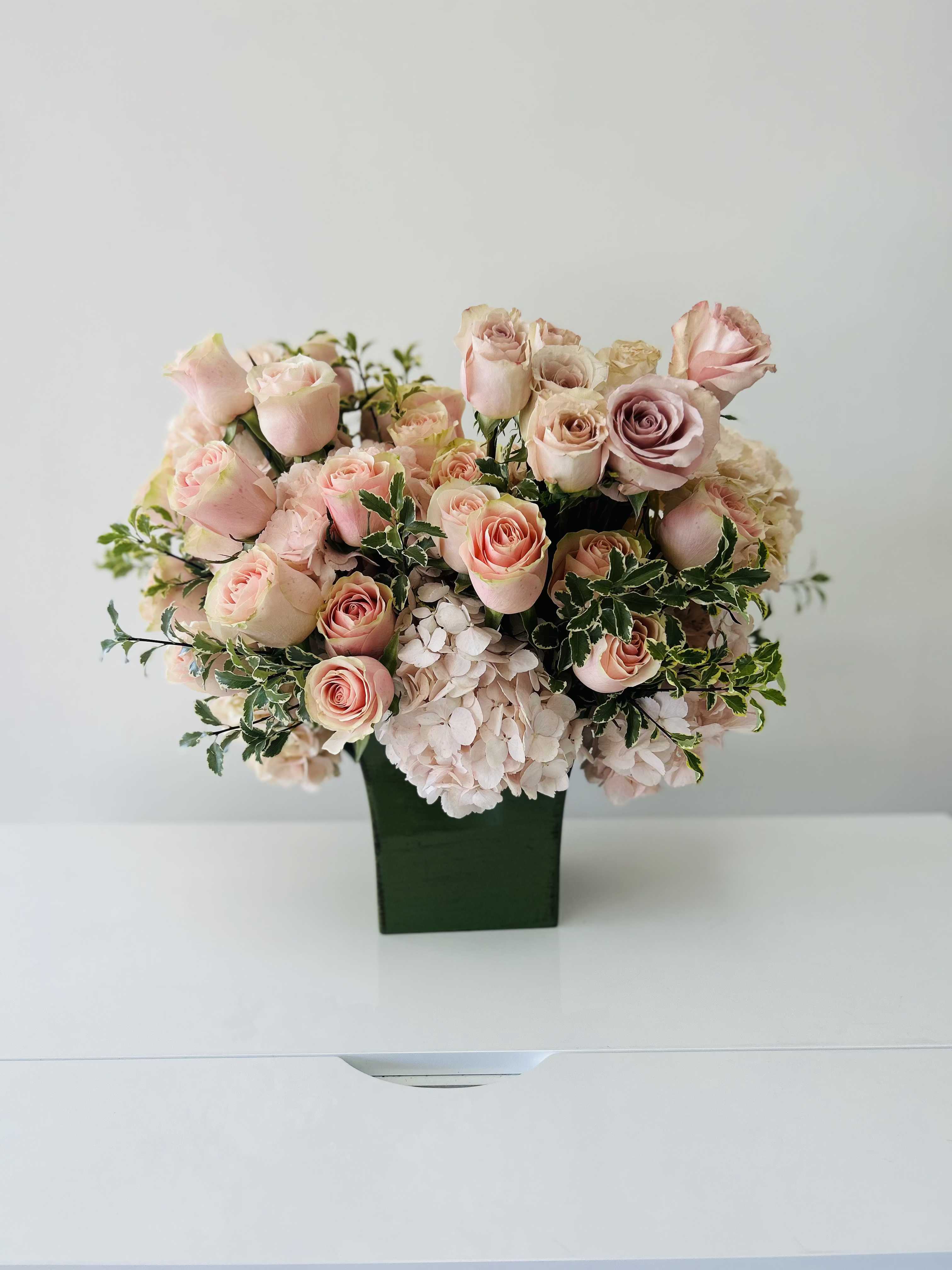 Pink roses and pale hydrangeas arranged in a green vase