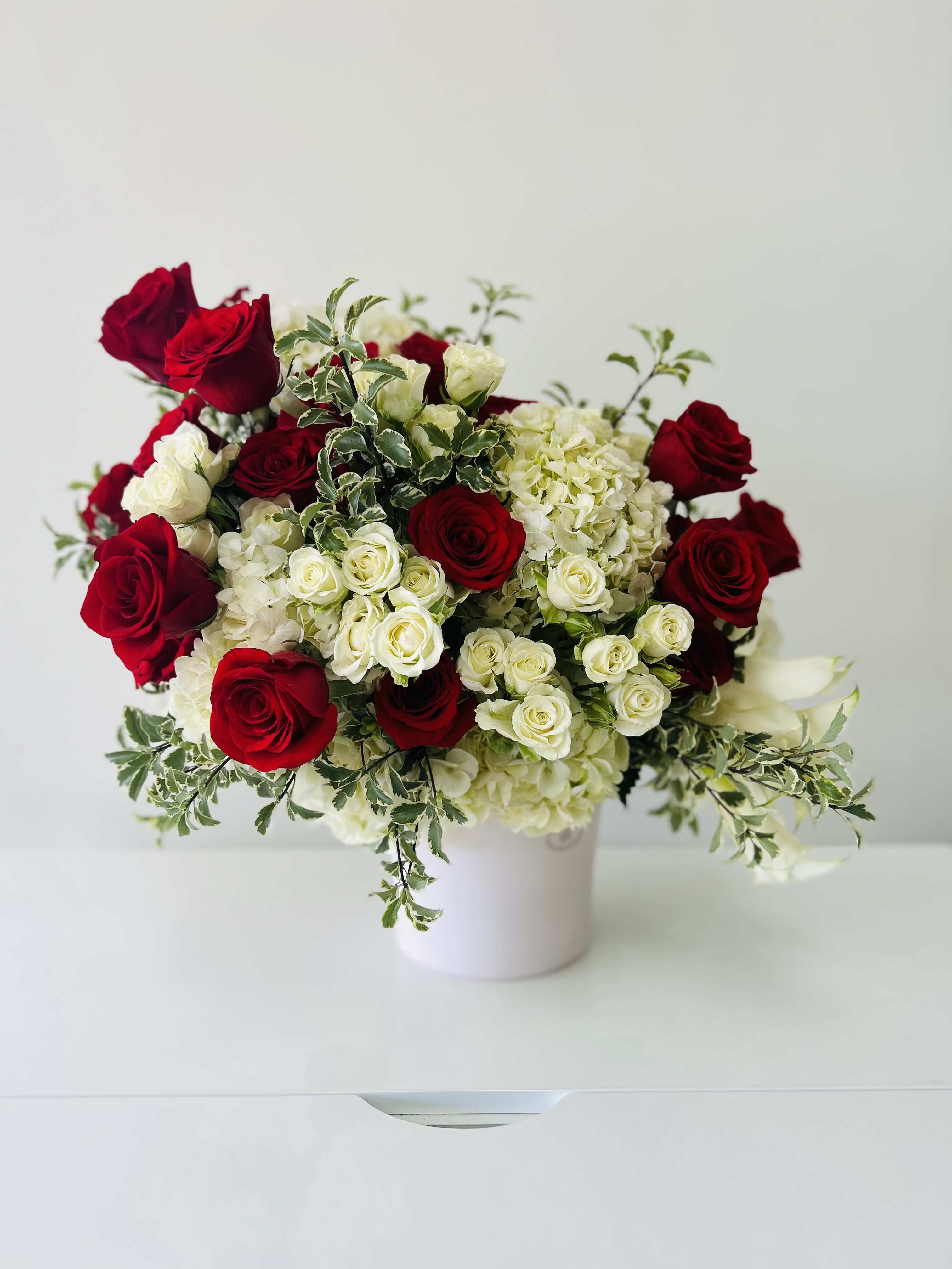 Red and white roses arranged in a white vase