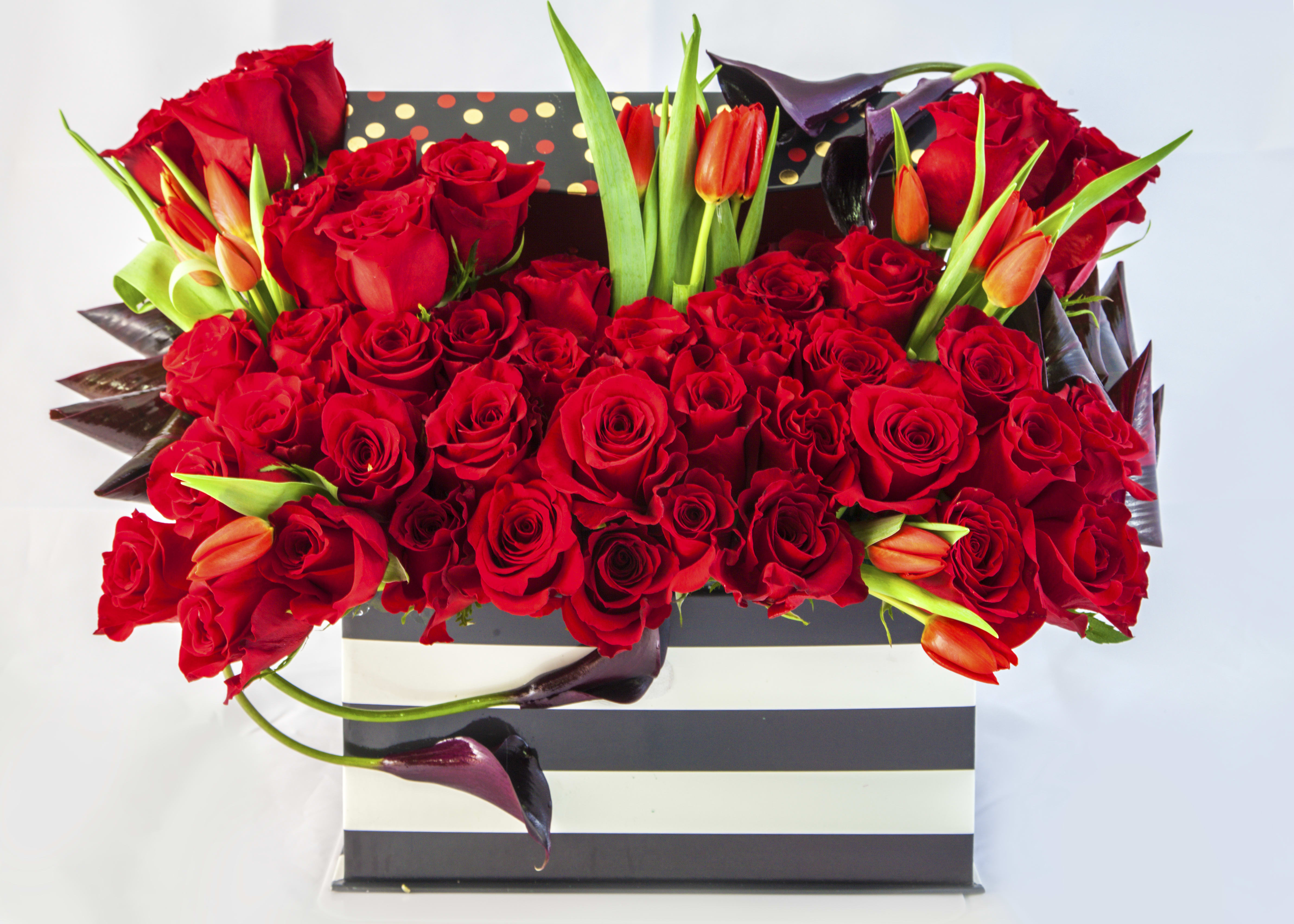 Red roses and orange tulips in a striped gift box