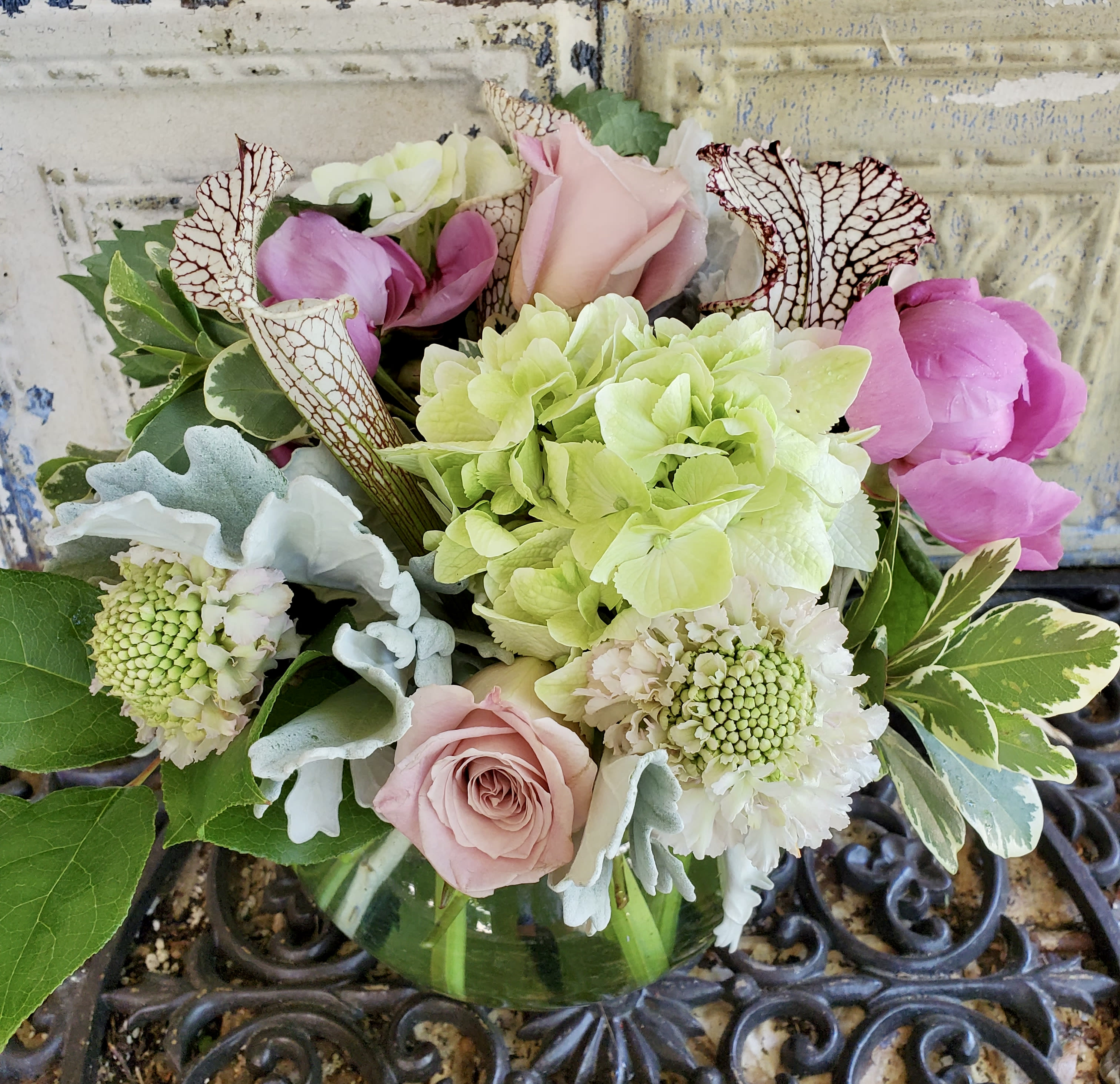 Mixed bouquet of pink roses, hydrangea, and white blooms in a glass vase