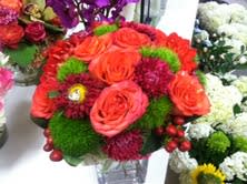 Orange roses and red flowers in a clear vase