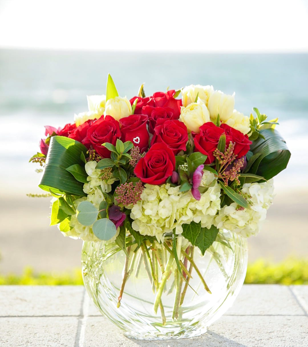 Red and white rose bouquet in a clear glass vase