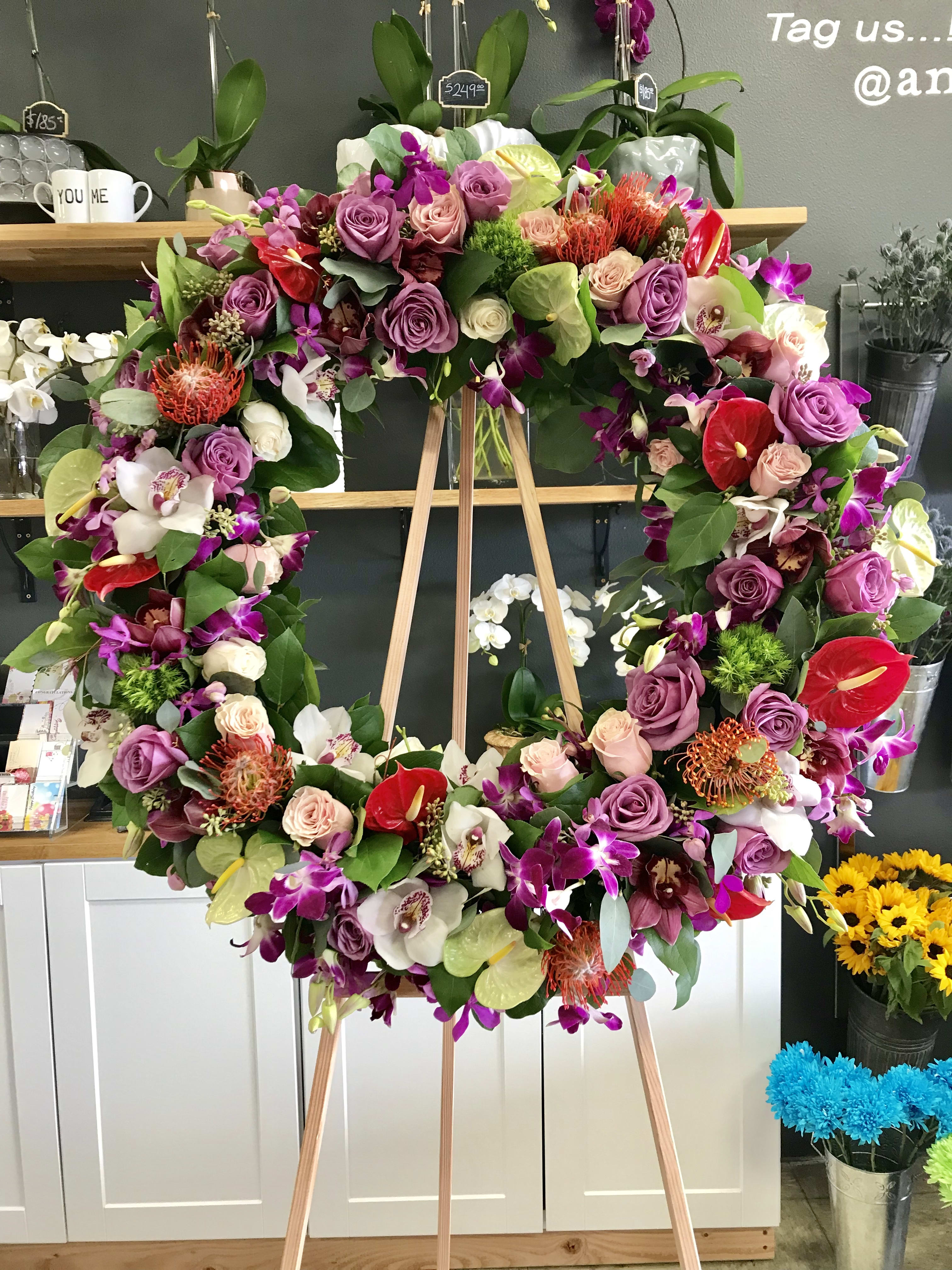 Large floral wreath on a wooden easel with purple, pink, white, and red blooms