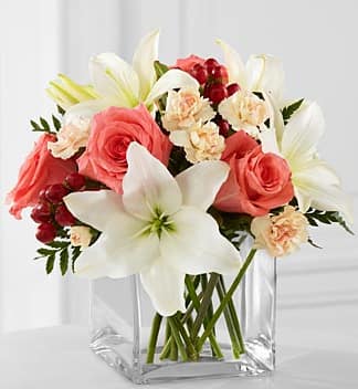 The FTD Blushing Beauty Bouquet - The FTD Blushing Beauty Bouquet is a simply stunning bouquet of floral elegance and grace. Coral roses are set to capture their attention arranged amongst white Asiatic lilies, peach mini carnations, red hypericum berries and lush greens. Presented in a clear glass cubed vase, this bouquet creates a wonderful gift of blooming beauty. GOOD bouquet includes 9 stems. Approx. 9âH x 10âW. BETTER bouquet includes 13 stems. Approx. 10âH x 11âW. BEST bouquet includes 16 stems. Approx. 11âH x 13âW.