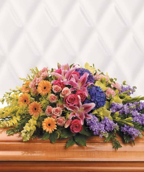 Colorful casket spray with lilies, roses, gerbera daisies, and hydrangeas