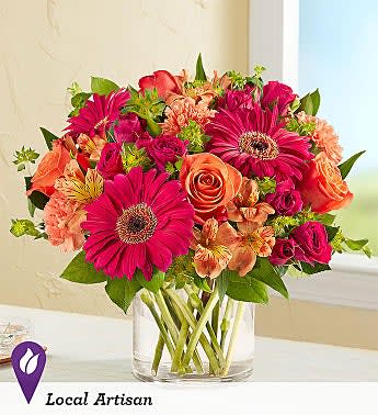 Mixed bouquet of pink and orange flowers in a clear glass vase