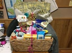 Gift basket with assorted packaged items and a pink ribbon