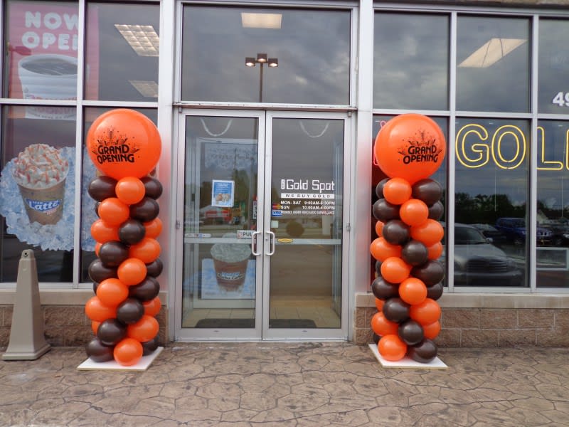 Orange and black balloon columns flank a storefront entrance