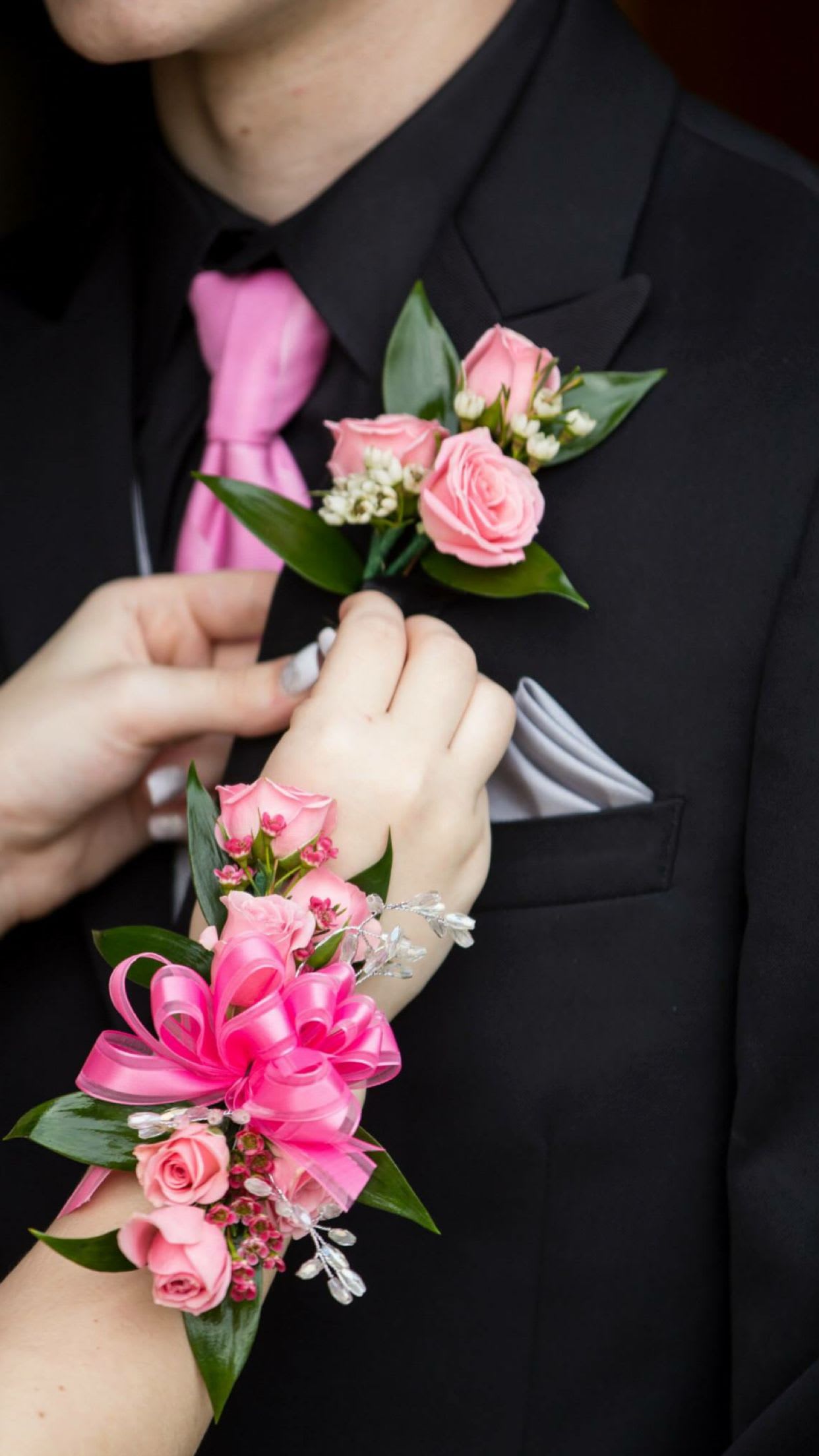 Pink rose boutonniere and corsage on a black suit and wrist