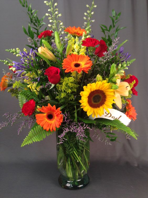 Colorful mixed bouquet in a glass vase with a "Dad" ribbon
