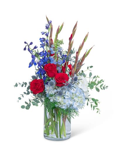 Red roses and blue flowers in a clear glass vase