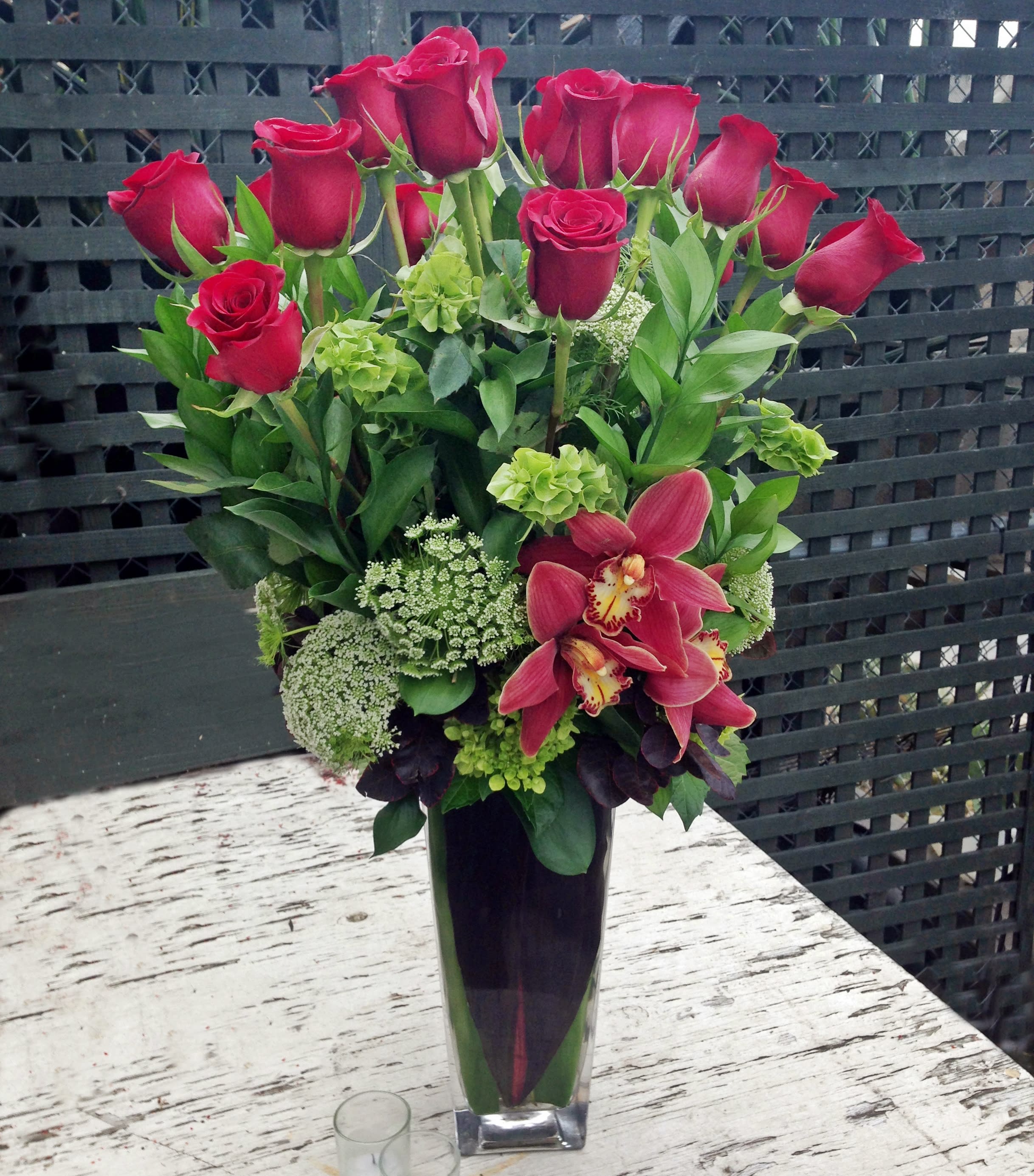 Red roses and pink orchids in a tall glass vase