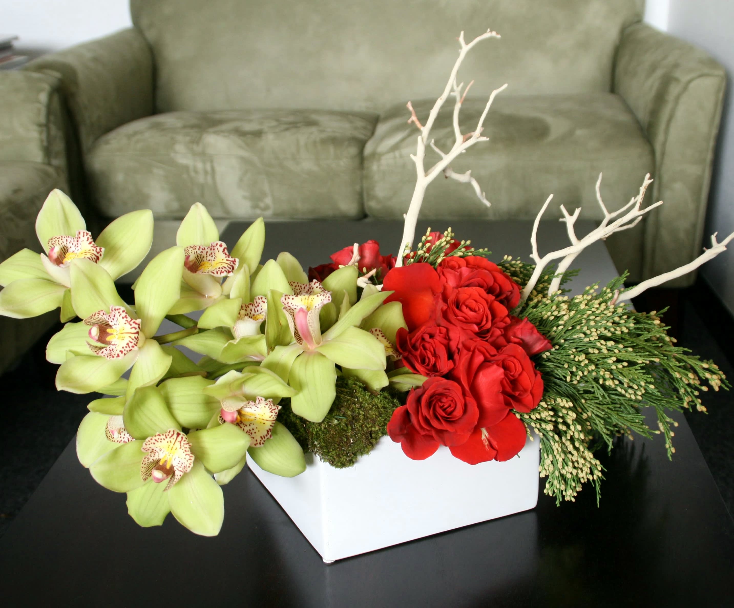 Red roses and green orchids in a white rectangular vase
