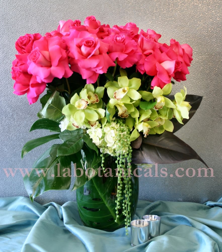 Pink roses and green orchids arranged in a glass vase