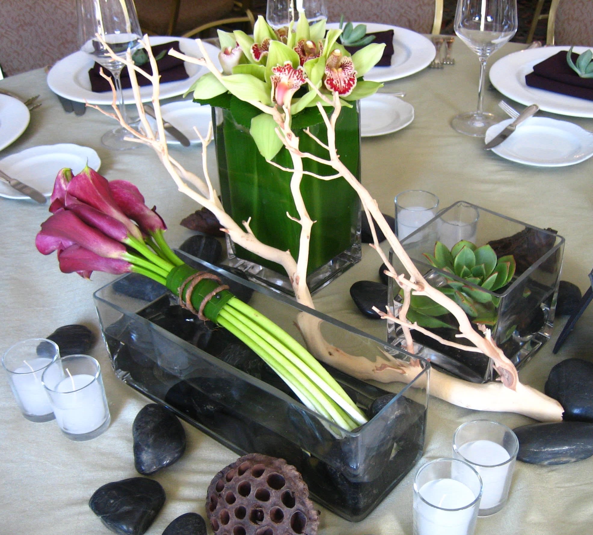 Table centerpiece with orchids, calla lilies, and succulents in glass containers