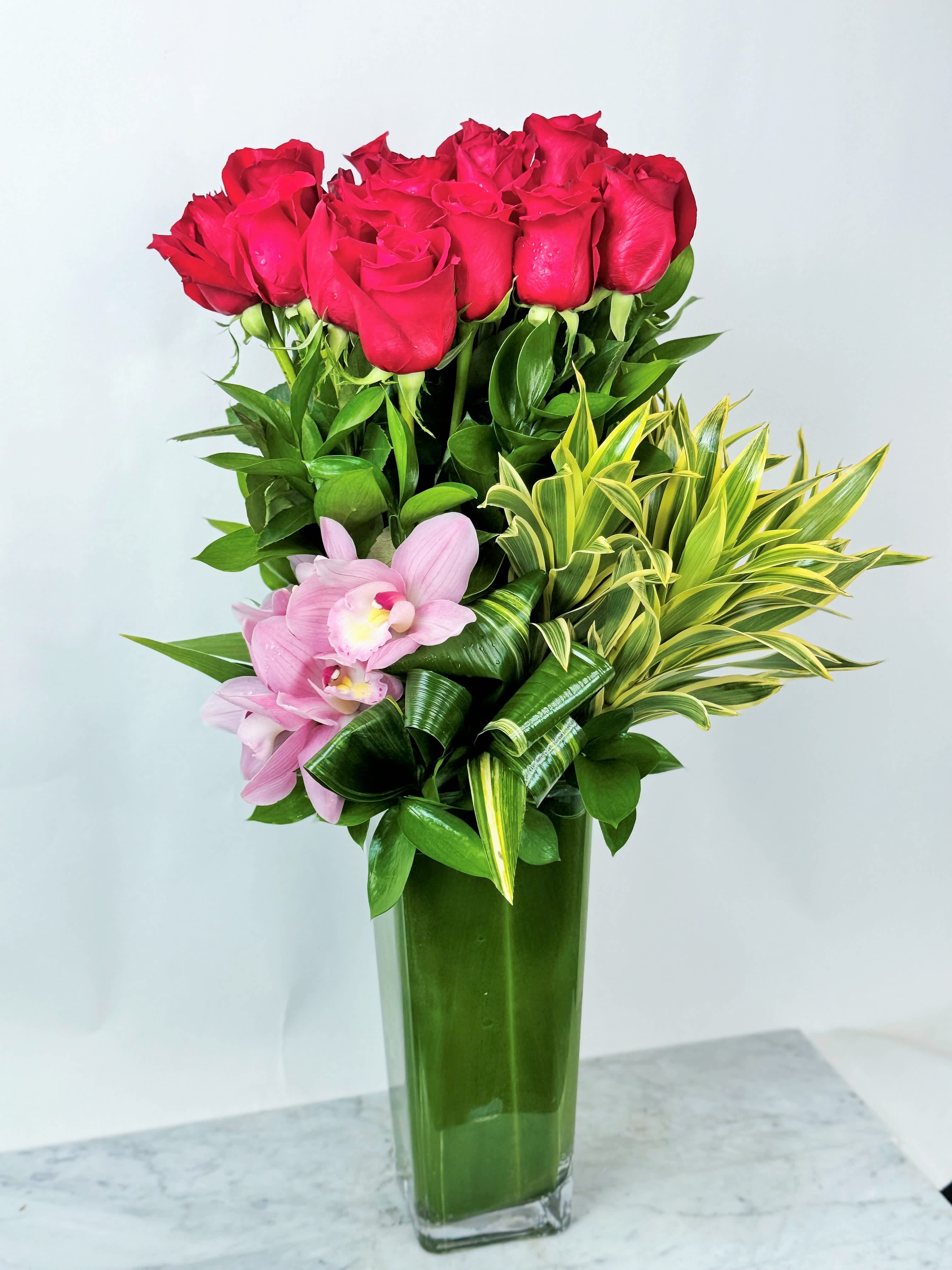 Red roses and pink orchids in a tall glass vase