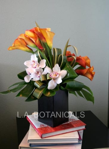 Orange calla lilies and white orchids in a black box arrangement