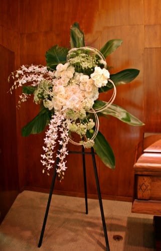 Standing floral spray with pale pink and white blooms on a black easel