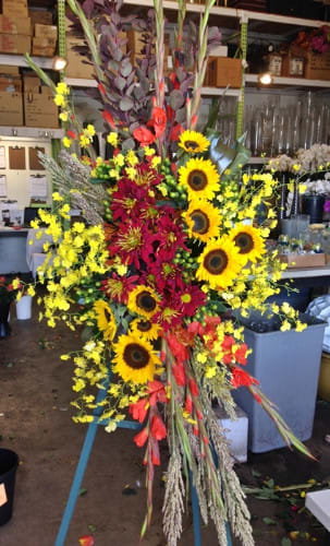 Tall floral arrangement with sunflowers, red blooms, and yellow accents